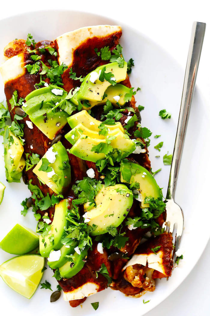 white plate, healthy recipes for weight loss, cauliflower enchiladas, avocado slices, parsley on top