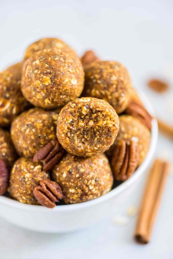 cinnamon sticks, chocolate peanut butter protein balls, walnuts and bites, in a white bowl