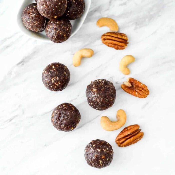 healthy energy balls, in a white bowl, walnuts and peanuts, scattered on a marble countertop