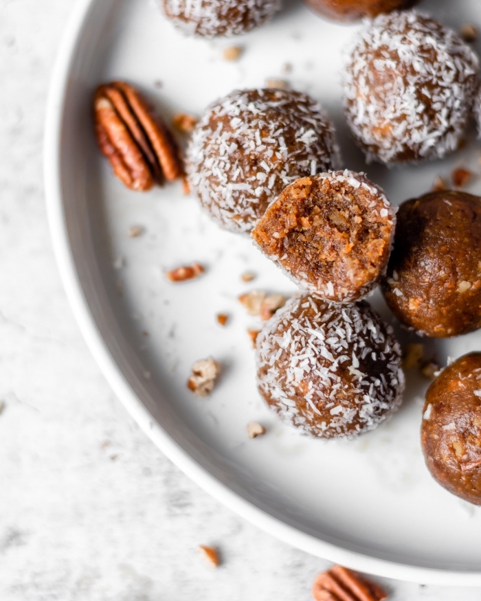 marble countertop, healthy energy balls, covered with coconut flakes, walnuts in white palte