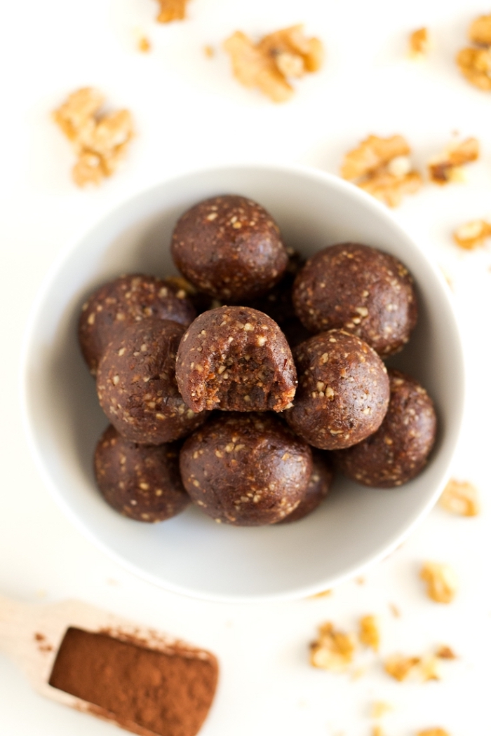 chocolate truffles, in white bowl, walnuts scattered around, cocoa in a wooden spoon, healthy energy balls recipe