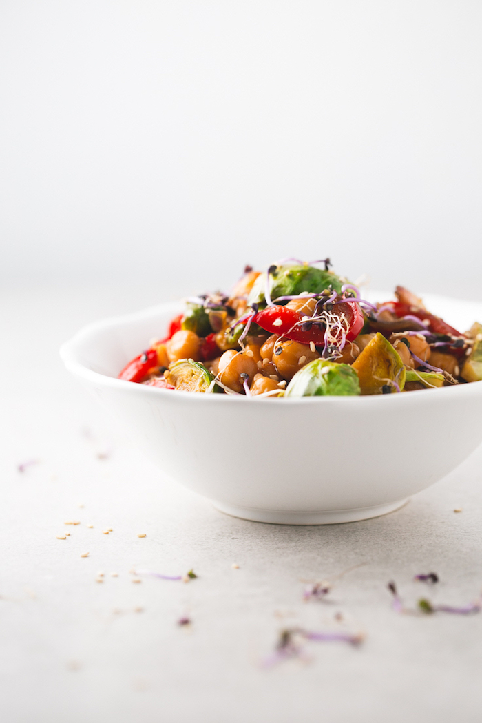 white table, healthy dinner ideas, chickpeas and vegetables stir fry, in white ceramic bowl, with sesame seeds