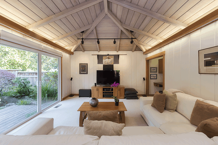 white wooden walls, white corner sofa, brown throw pillows, vaulted vs cathedral ceiling, wooden coffee table