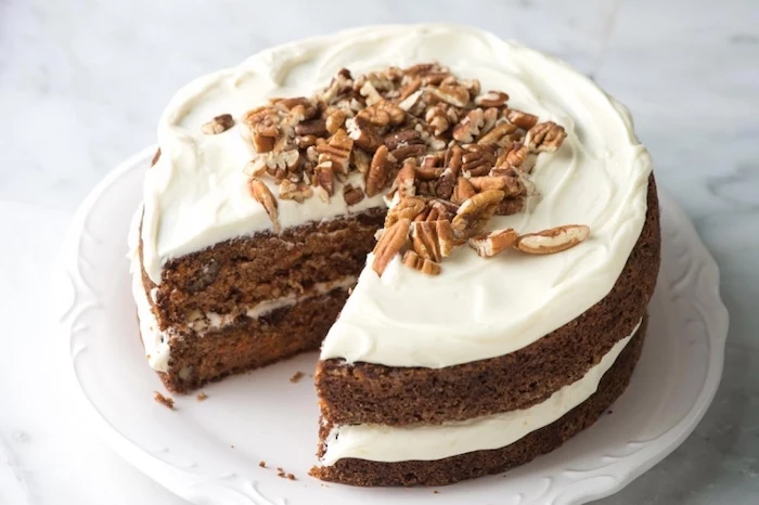 carrot cake, thanksgiving desserts ideas, white frosting, crushed walnuts, white plate, marble countertop