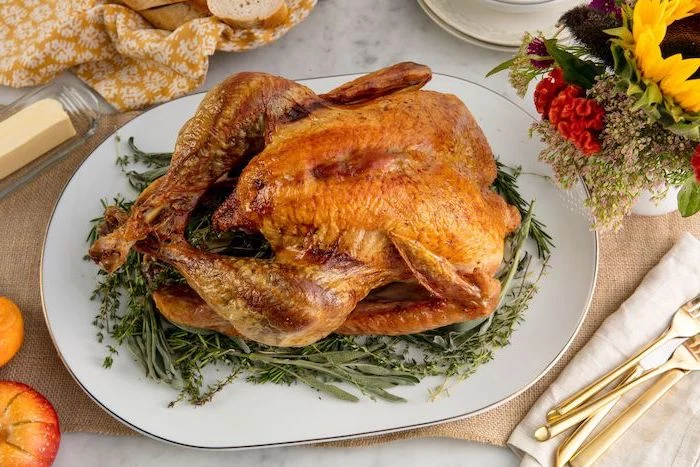 roasted turkey, fresh herbs, white plate, flower bouquet, how to make a turkey for thanksgiving