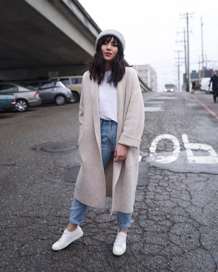 woman in the middle of the street, wearing long coat and jeans, medium length hairstyles with bangs, white sneakers