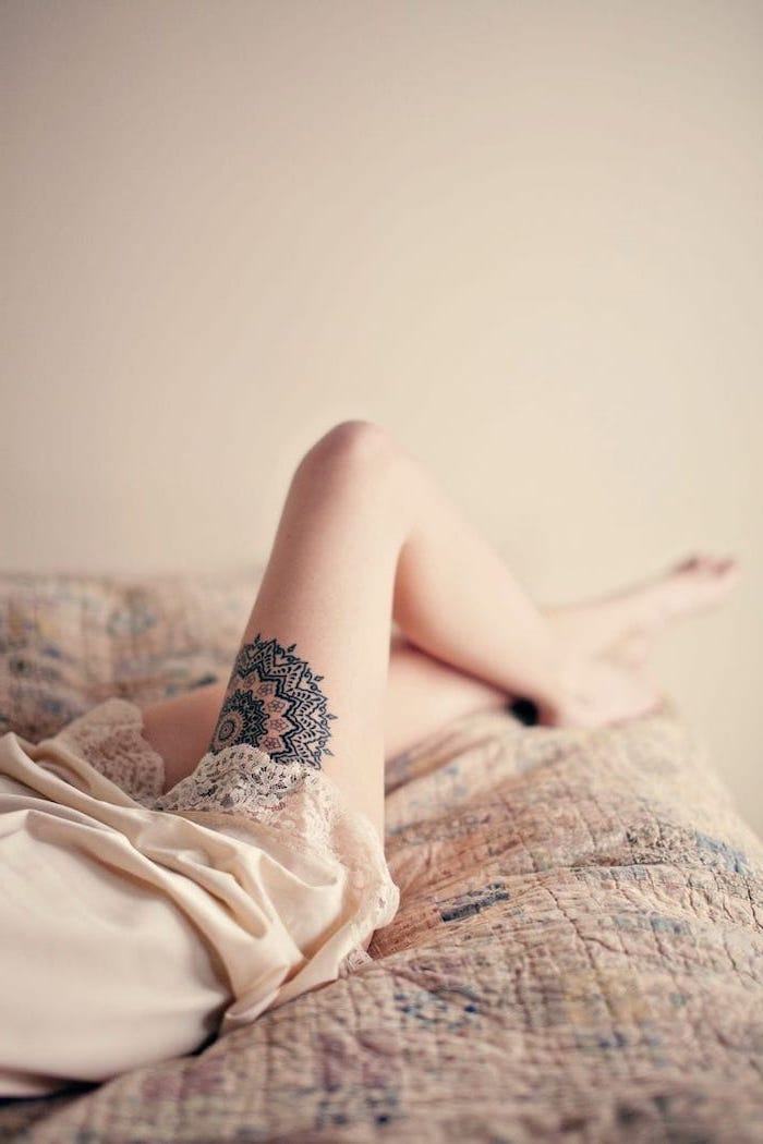 woman laying on bed, mandala flower tattoo, cute thigh tattoos, white silk night gown