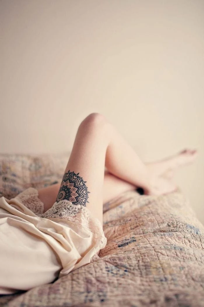 woman laying on bed, mandala flower tattoo, cute thigh tattoos, white silk night gown