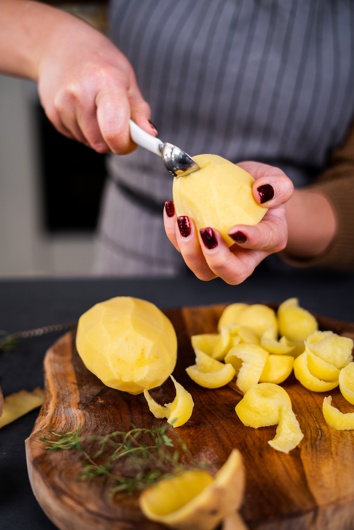 woman with red glitter nail polish, scooping out potatoes, placing them on wooden board, baked potato volcanoes