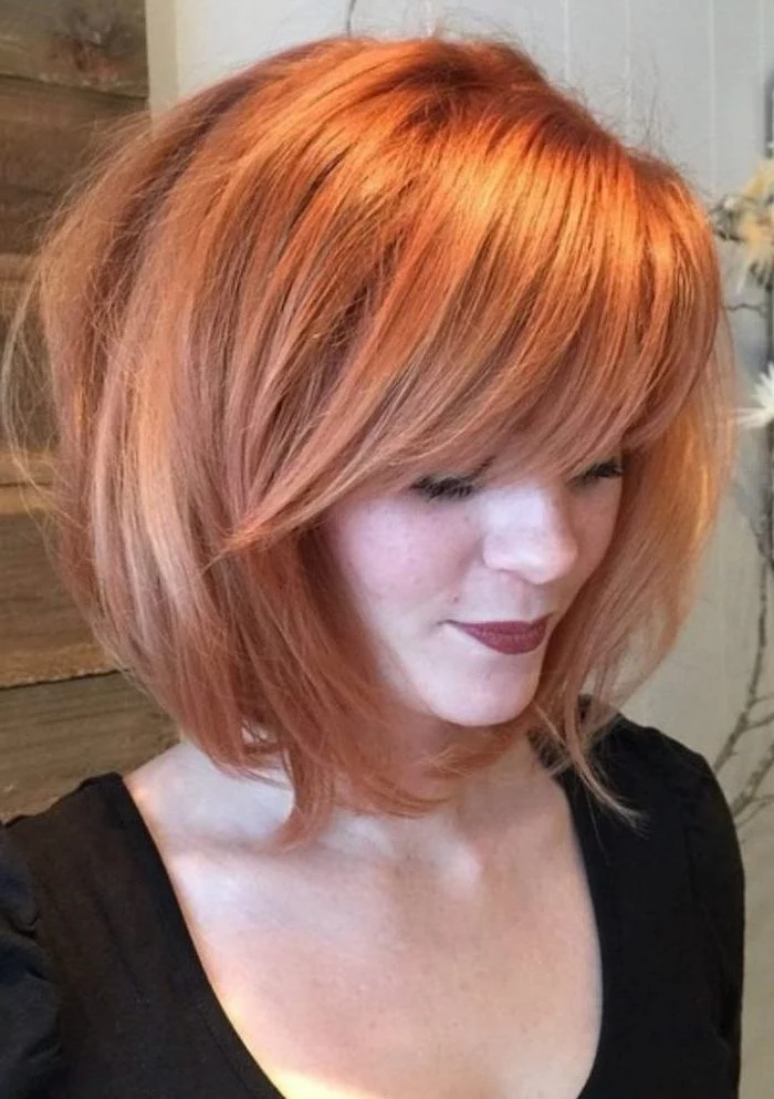 woman with red hair, asymmetrical bob with side swept bangs, wearing black top, medium hairstyles 2019