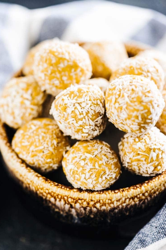 peanut butter, healthy energy balls recipe, covered with coconut flakes, in wooden bowl
