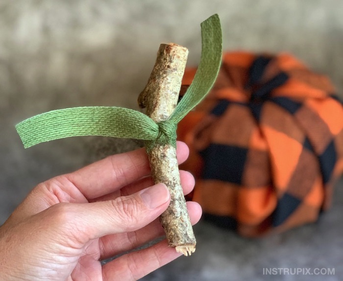 hand holding, wooden stick, green ribbon around it, fall decor, step by step, diy tutorial