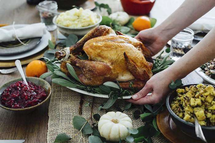 serving roasted turkey, with fresh herbs, on the side, cranberry sauce, how to make a turkey for thanksgiving, wooden table