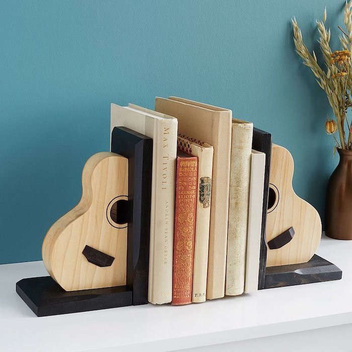 acoustic guitar bookends, christmas gift ideas for him, books in between them, placed on white surface, blue wall background