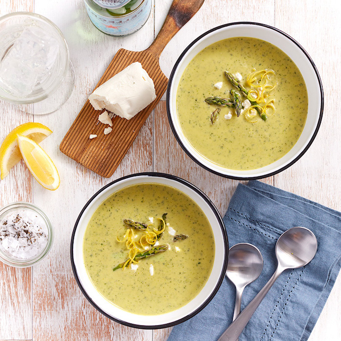 two white bowls, full of soup, asparagus for garnish, cream of chicken soup recipe, blue table cloth, wooden table