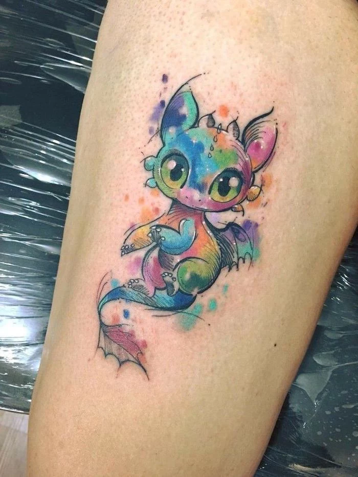 watercolor baby toothless tattoo, thigh tattoo, japanese dragon tattoo, leg leaning on black leather chair