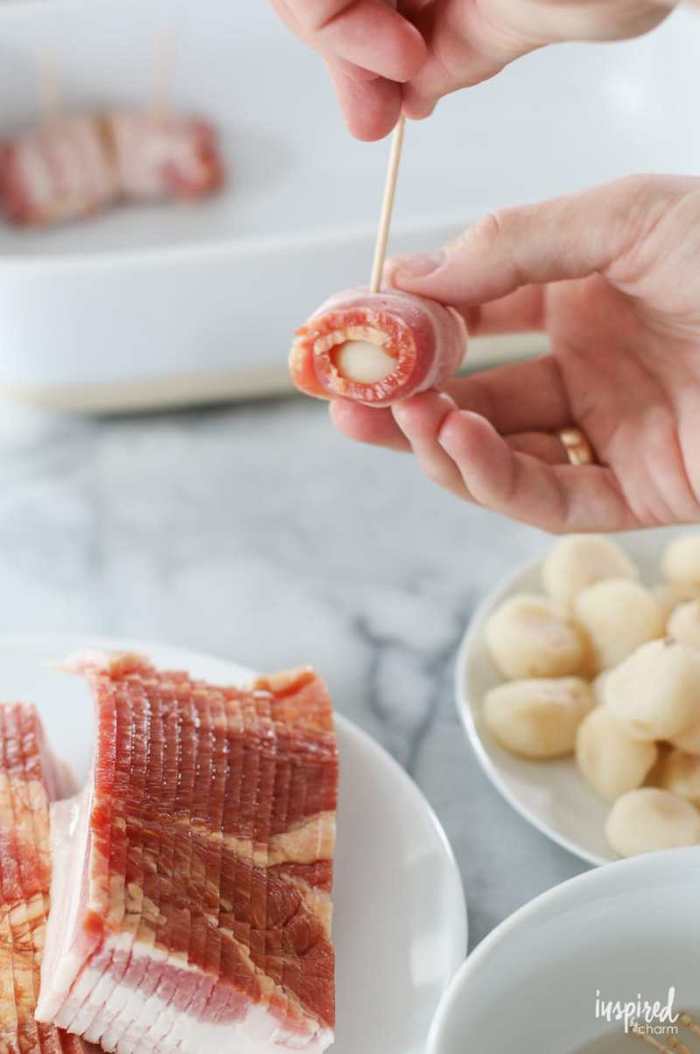 bacon slices arranged on white plate, christmas appetizers, chestnuts wrapped in bacon, held together by a toothpick