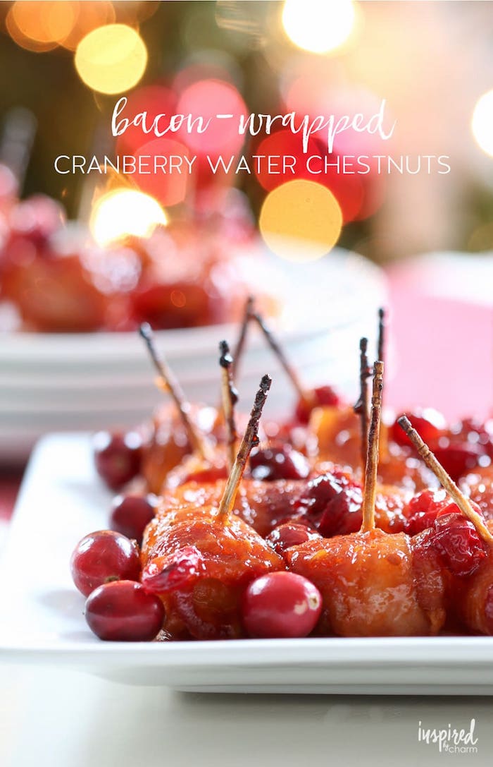 bacon wrapped cranberry water chestnuts, christmas appetizers, placed on white plate, fresh cranberries on the side