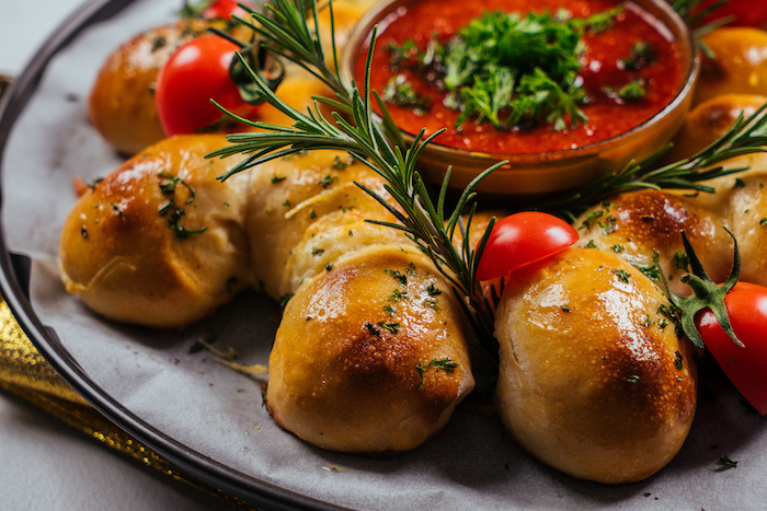 pull apart christmas bread, rosemary branches and halved cherry tomatoes, tomato salsa in a bowl in the middle