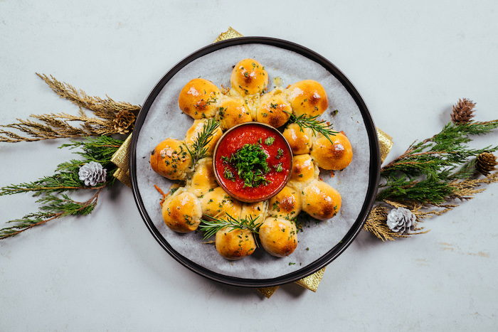 pull apart christmas bread, in the shape of a wreath, tomato salsa in a bowl in the middle, paper lined baking sheet