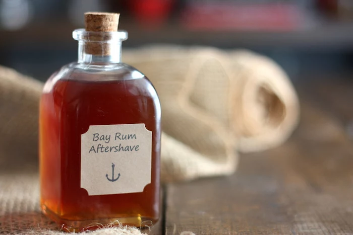 bay rum aftershave in small bottle with cork cap, step by step diy tutorial, christmas gifts for boyfriend, placed on wooden surface
