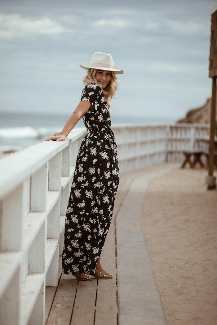 woman leaning on white wooden fence, wearing a long floral dress and hat, 2019 fashion trends, blonde hair