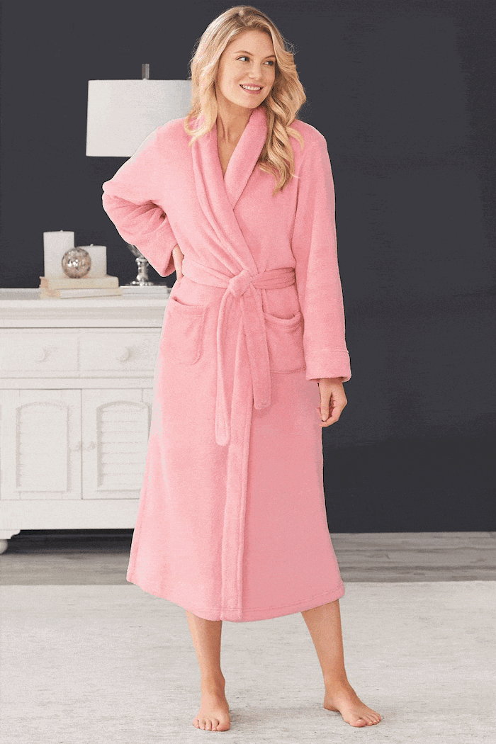 woman with blonde hair, wearing a cozy pink robe, what to get mom for christmas, black wall in the background
