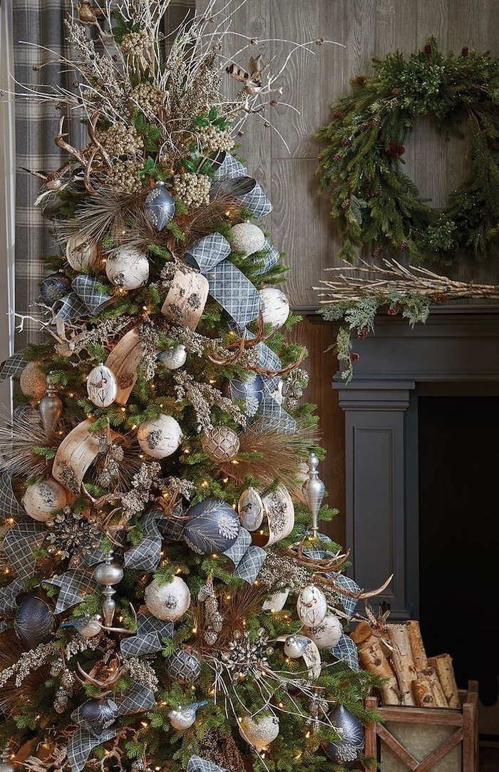 decorated tree next to the fireplace, christmas tree decorating ideas, blue and silver ornaments with blue and gold ribbons