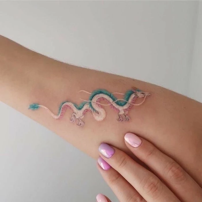 white and blue dragon with red shadows, forearm tattoo, red dragon tattoo, woman with pink nail polish