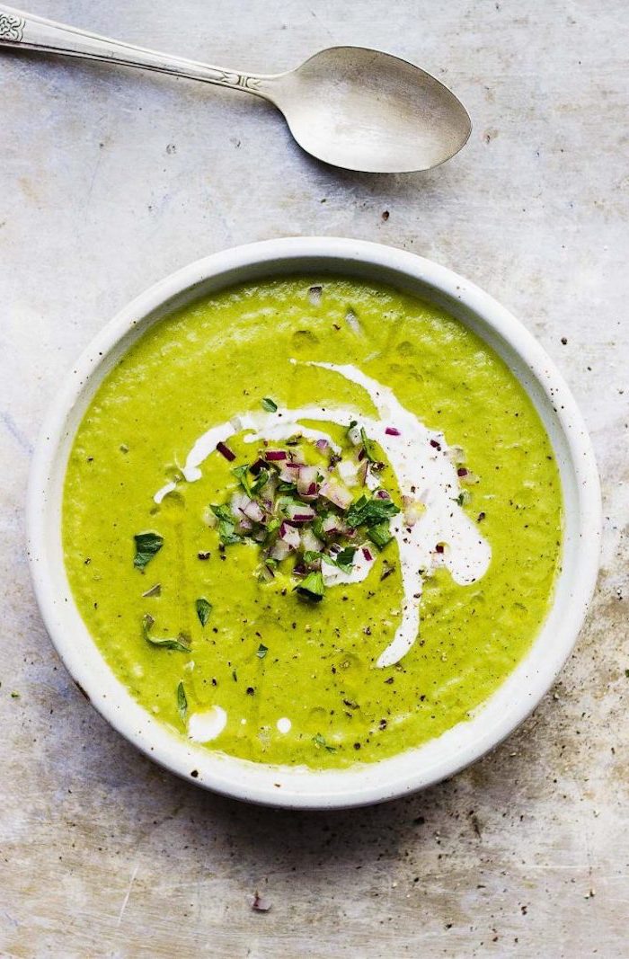 how to make potato soup, cream soup in a white ceramic bowl, onion and fresh herbs for garnish