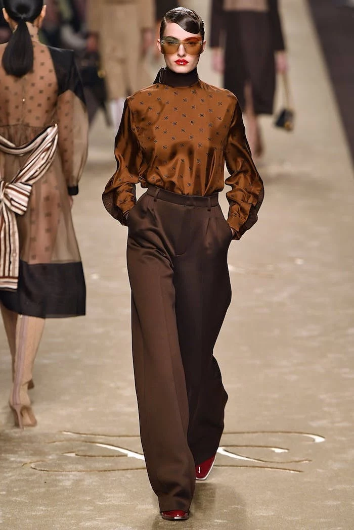 model walking down the runway, wearing brown pants and blouse, 2019 fashion trend forecast, red boots