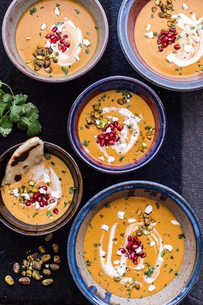 ceramic bowls full of soup, pomegranate seeds on top for garnish, how to make potato soup, black table cloth