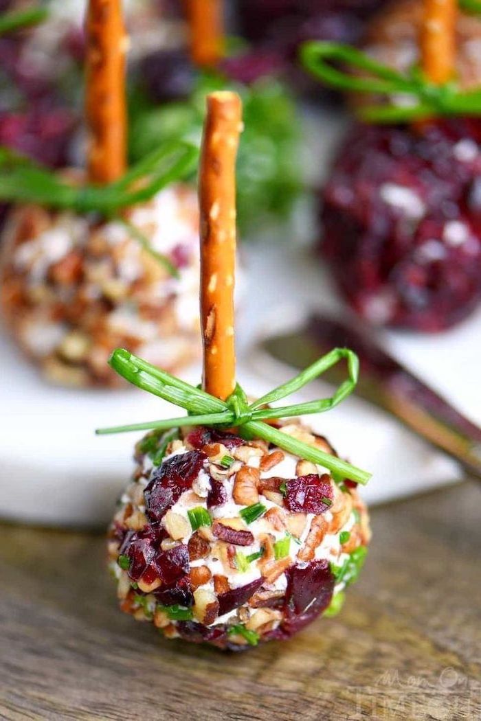cheese balls dipped in crushed nuts and cranberries, christmas appetizer ideas, placed on wooden surface
