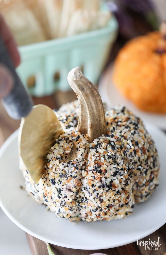 cheeseball in the shape of a pumpkin, covered with sesame seeds, easy christmas appetizers, placed on white plate