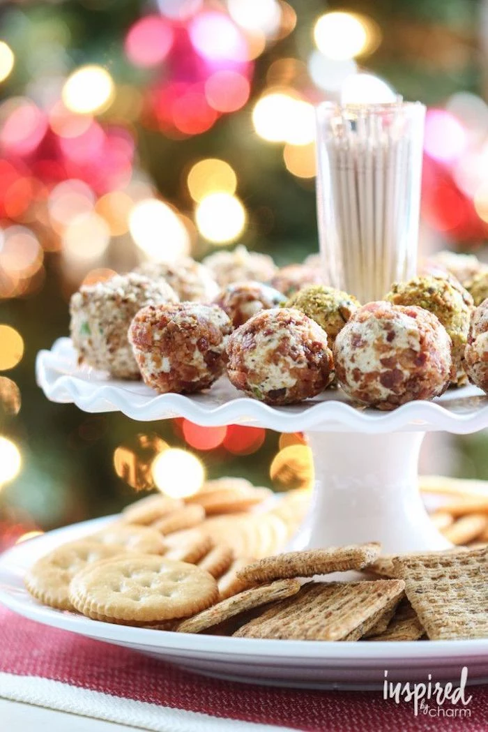 cheese truffles covered with chopped nuts, arranged on white plate, finger foods for party, different types of crackers