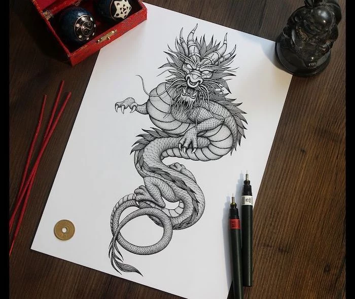 wooden table, black and white pencil sketch on it, red dragon tattoo, scary large dragon drawing