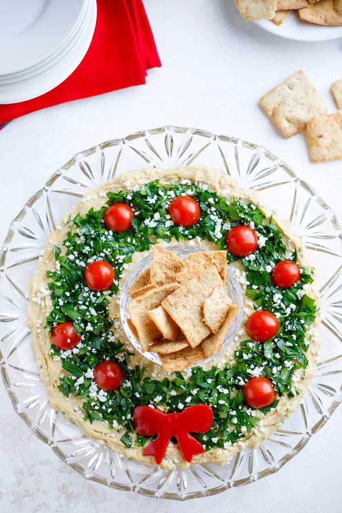 wreath made of hummus, chopped herbs and crumbled feta cheese and tomatoes on top, easy christmas appetizers finger foods