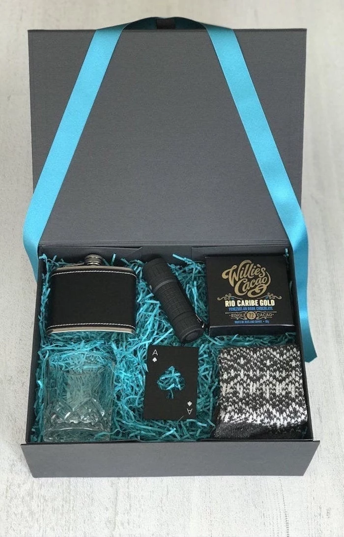 luxurious box with blue ribbons and paper inside, cute gifts for boyfriend, flask whiskey glass and deck of cards inside