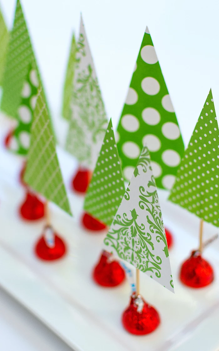 easy christmas crafts for kids, christmas trees, made of green paper and hershey's kisses, placed on white plate