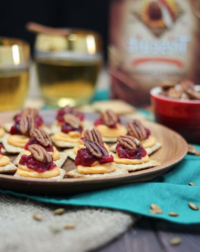 crackers with sweet potato puree, cranberry sauce and walnuts, easy party snacks, arranged on wooden plate