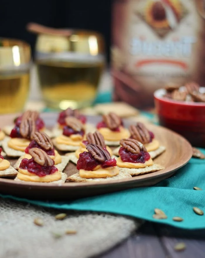 crackers with sweet potato puree, cranberry sauce and walnuts, easy party snacks, arranged on wooden plate