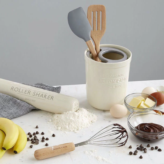 wooden set of baking utensils, personalised gifts for mom, bowls of butter and chocolate, bananas and eggs on the table