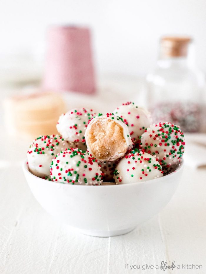 truffles decorated with white icing, red and green sprinkles on them, cookie icing recipe, placed in white bowl on wooden table