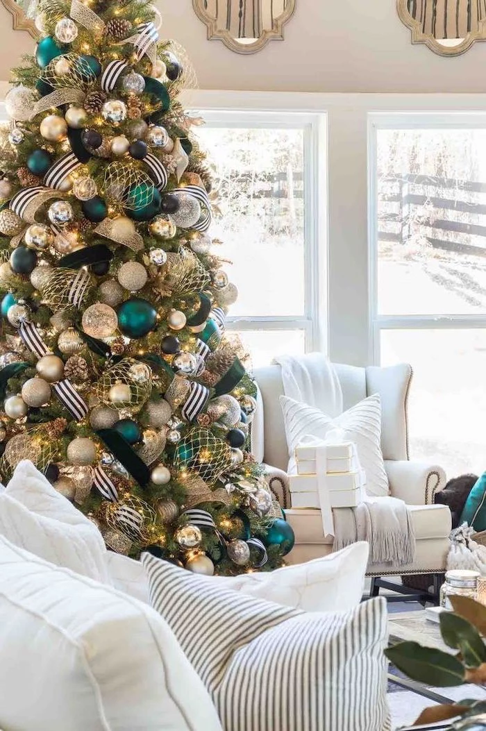 tall tree with black white and gold ribbons, turquoise silver and gold ornaments, christmas tree ribbon, next to white living room furniture