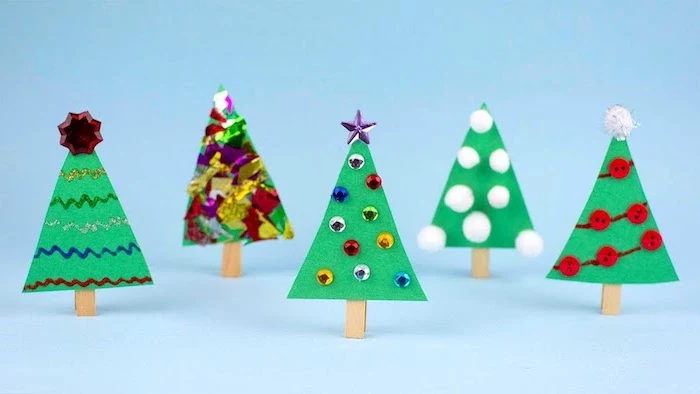 christmas activities for preschoolers, christmas trees made of felt, pompoms and colorful confetti, placed on blue surface