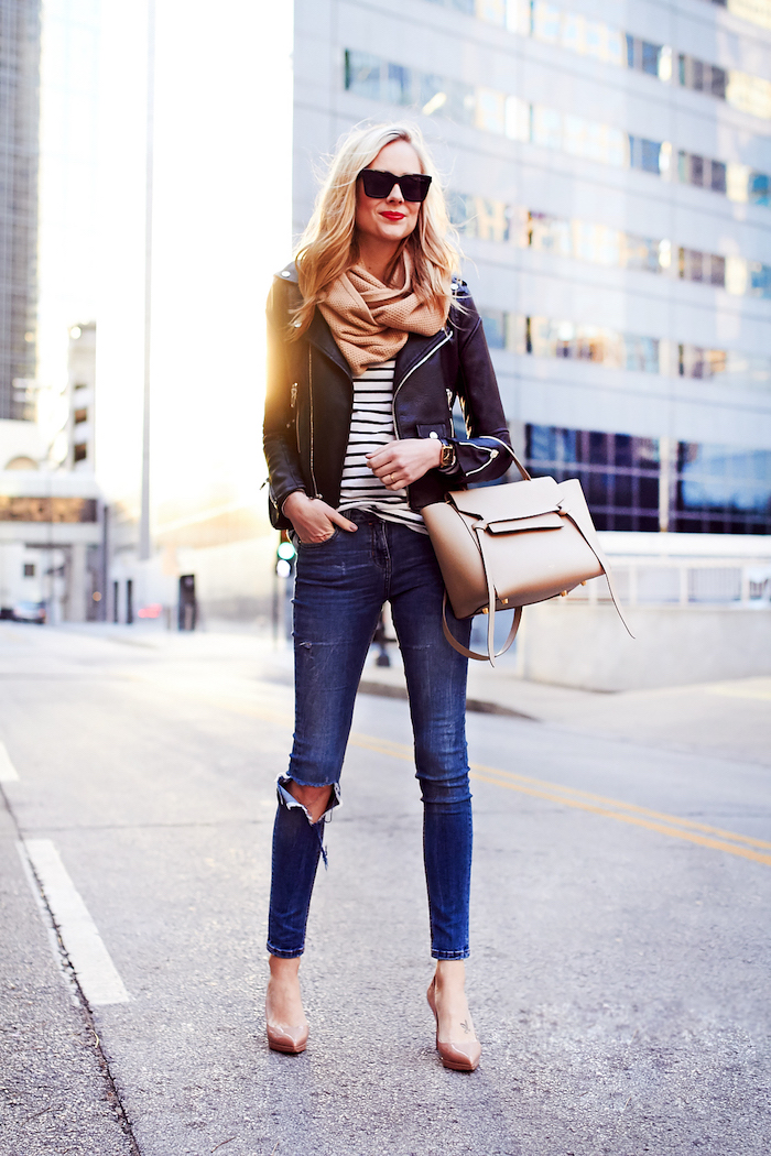 woman standing on the street, wearing jeans and black leather jacket, fall trends, nude heels scarf and leather bag