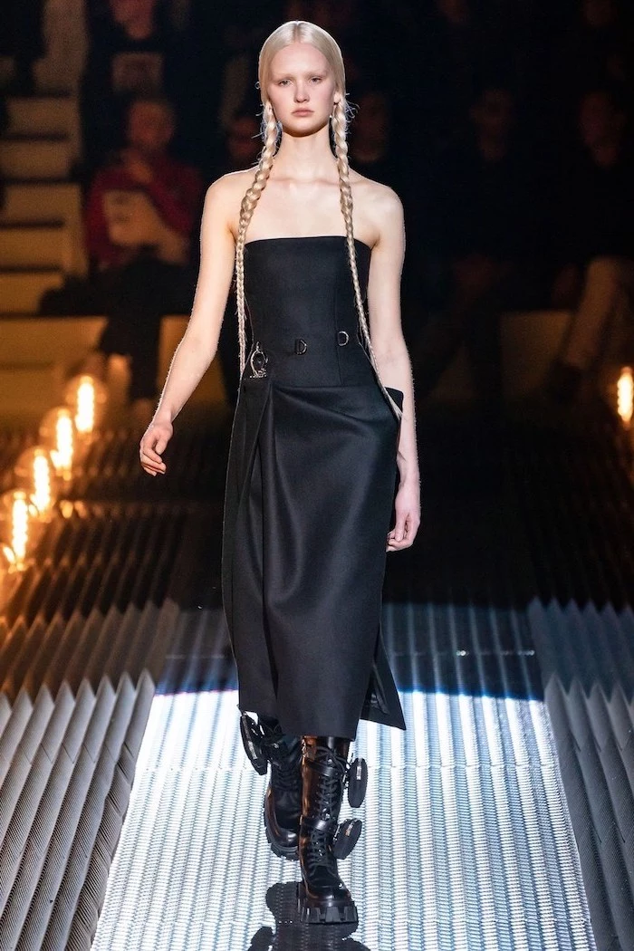 model with two long blonde braids, wearing a black dress with black boots, fall trends, walking down a runway
