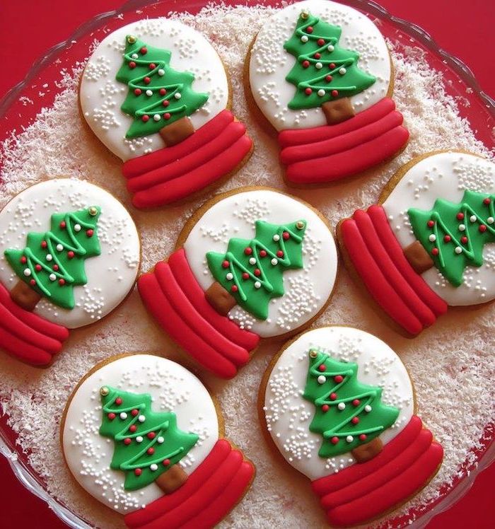 snow globe shaped cookies, cookie icing recipe, white red and green icing used for decoration, placed on faux snow in bowl