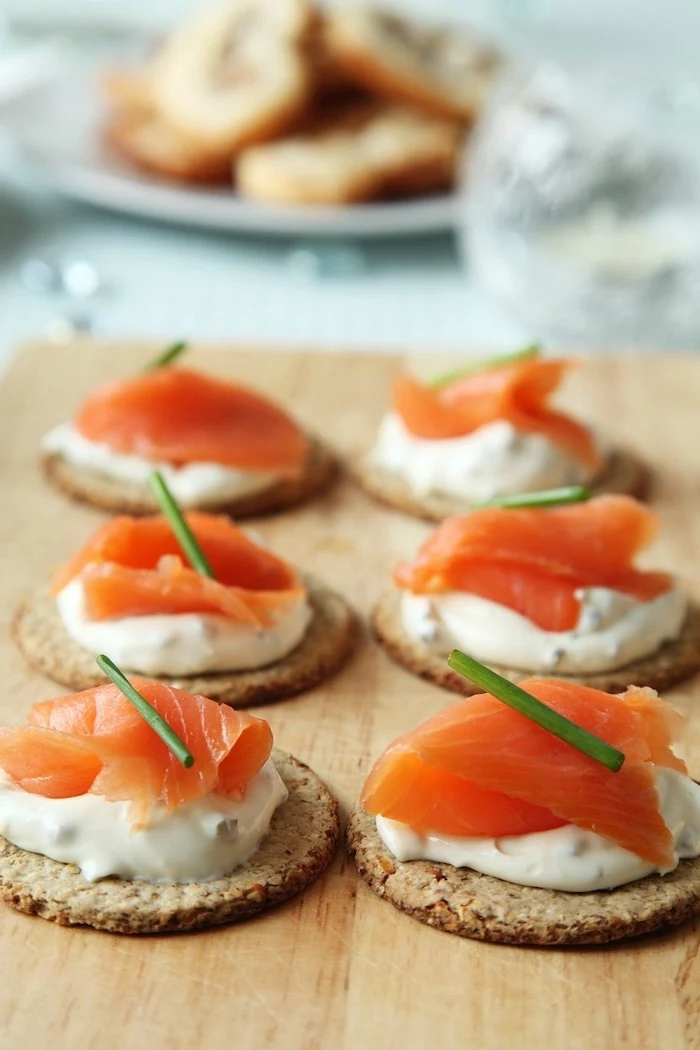 crackers with sour cream and salmon fillet, arranged on wooden board, easy christmas appetizers finger foods
