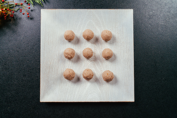 cream cheese christmas appetizers, cream cheese balls, arranged on wooden board, placed on black surface